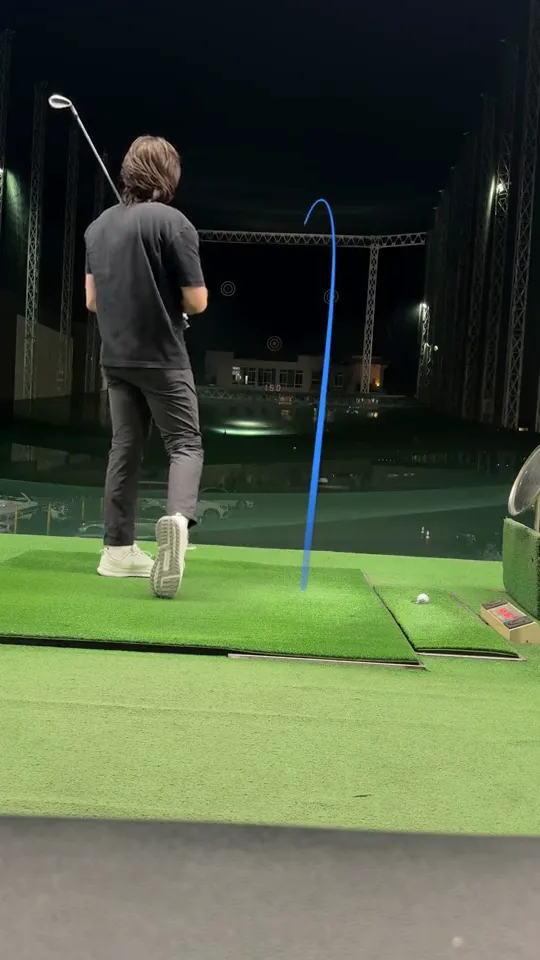 A night range swing with a blue ball-flight trace drawn by Comet